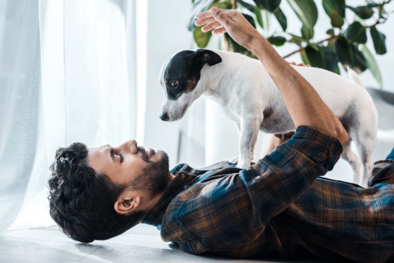 man lying down holding Jack Russell Terrier